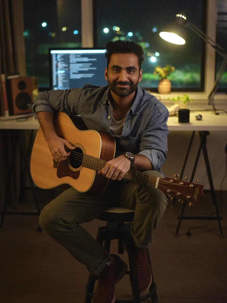 Aakash Pahuja in his studio at night, guitar in hand, black coffee on the desk.